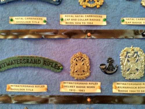 Display of South African Traditional Regiments cap/beret badges, shoulder titles and collar badges.