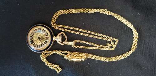 Miniature gold tone pocket watch on chain with blue enamel flower back