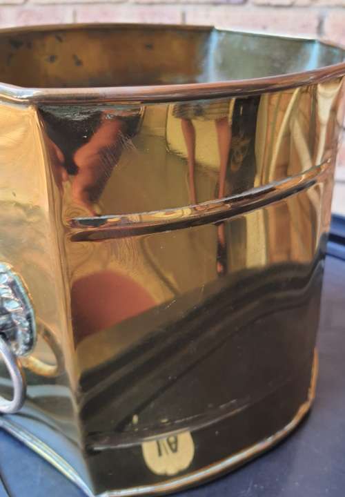 A BRASS VINTAGE PLANTER WITH LION HEAD HANDLES SOLD AS IS