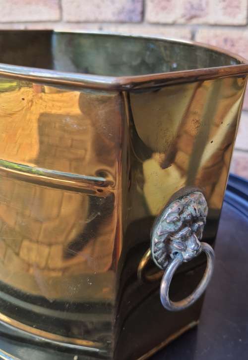 A BRASS VINTAGE PLANTER WITH LION HEAD HANDLES SOLD AS IS