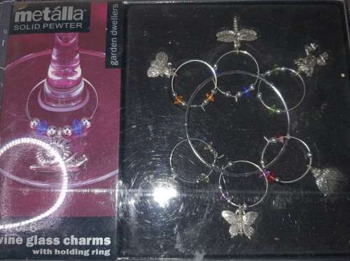 A SET OF WINE GLASS CHARMS ON A RING IN ITS ORIGINAL PACKAGING SOLD AS IS