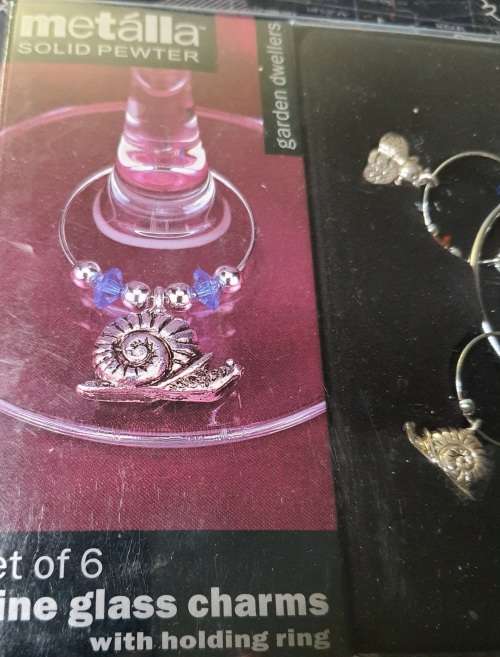 A SET OF WINE GLASS CHARMS ON A RING IN ITS ORIGINAL PACKAGING SOLD AS IS