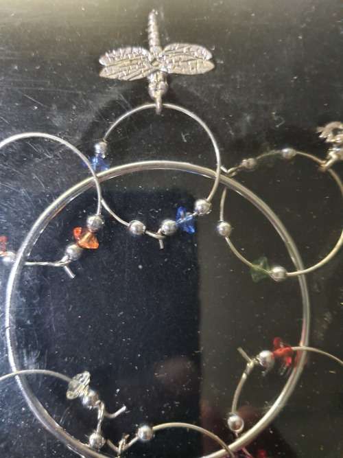 A SET OF WINE GLASS CHARMS ON A RING IN ITS ORIGINAL PACKAGING SOLD AS IS