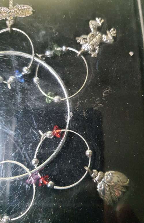 A SET OF WINE GLASS CHARMS ON A RING IN ITS ORIGINAL PACKAGING SOLD AS IS