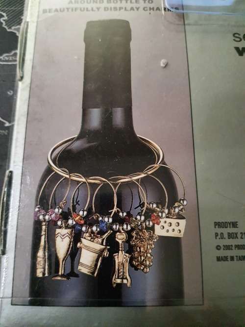 A SET OF WINE GLASS CHARMS ON A RING IN ITS ORIGINAL PACKAGING SOLD AS IS