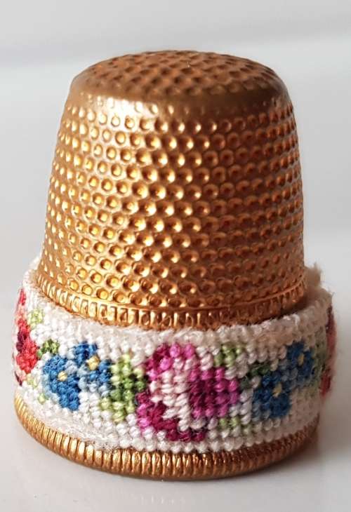 A Vintage collectors metal thimble. Thimble has small embroidered floral band