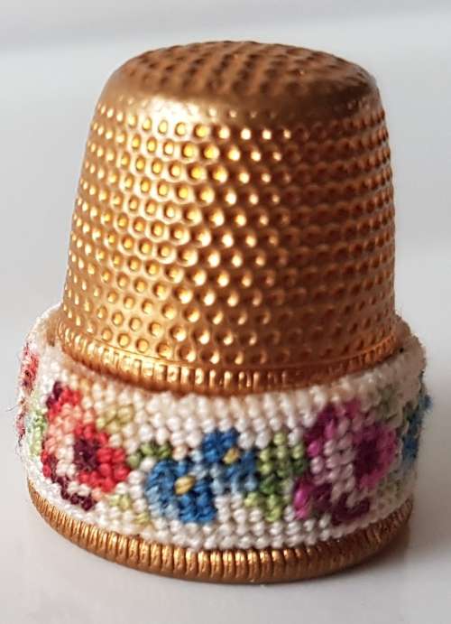 A Vintage collectors metal thimble. Thimble has small embroidered floral band