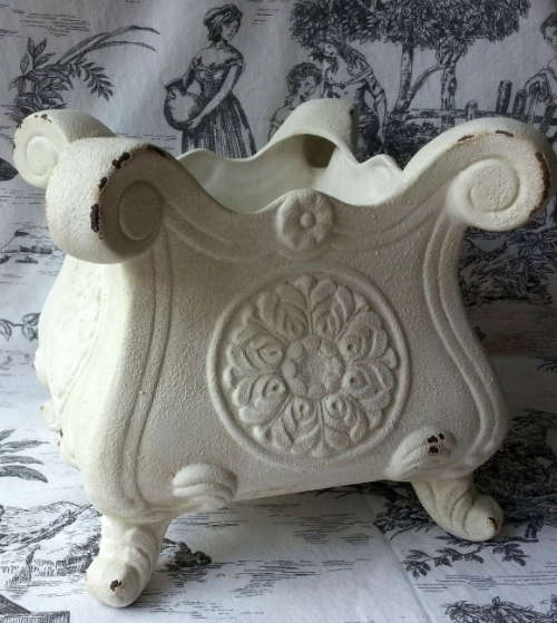 ATTRACTIVE, PAINTED OFF WHITE, ANTIQUED METAL POT PLANT HOLDER ON FOUR LEGS.