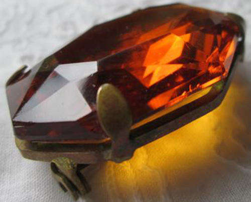 VINTAGE LARGE BROOCH WITH AN AMBER COLOURED GLASS STONE SET IN GILT METAL.
