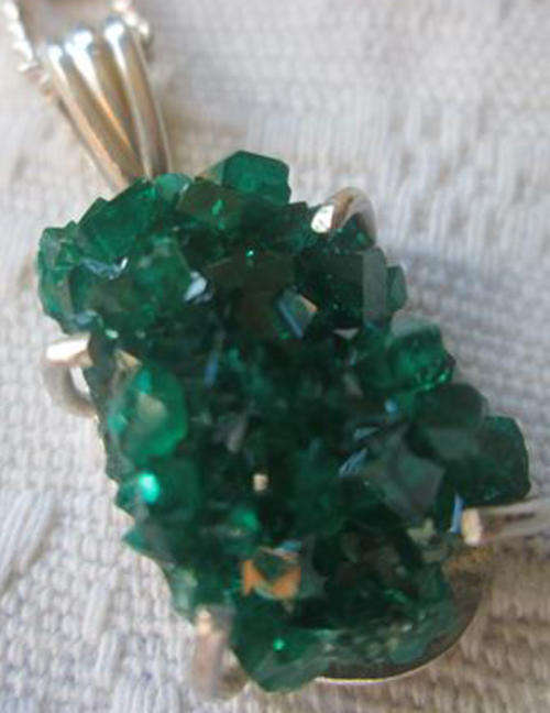 BEAUTIFUL DIOPTASE CLUSTER FROM TSUMB MINES NAMIBIA SET IN SILVER AS A PENDANT WITH A SILVER CHAIN.
