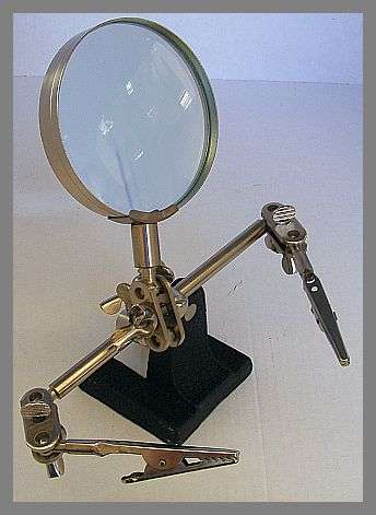MAGNIFYING GLASS WITH PRONG HANDS ON A SOLID STAND