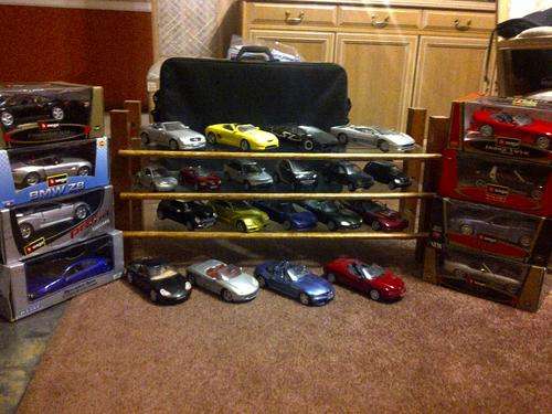 Collection of 27 Burago model cars with glass stand