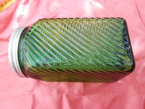 Green, ribbed-glass jar with metal lid.