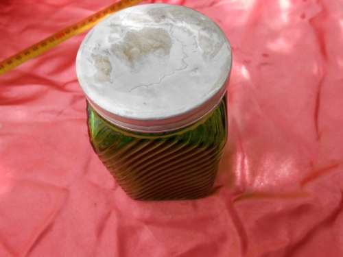 Green, ribbed-glass jar with metal lid.