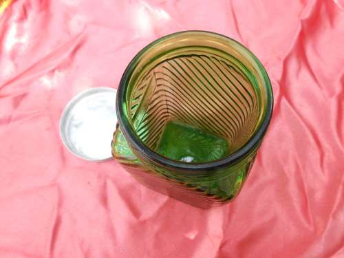 Green, ribbed-glass jar with metal lid.