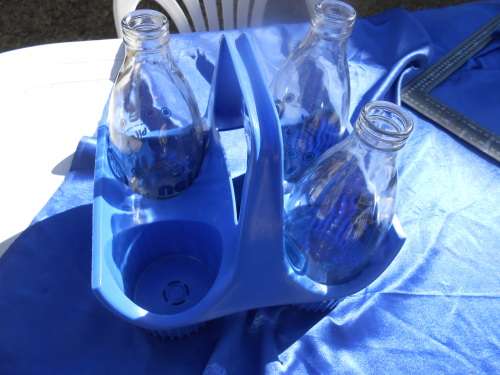Three glass milk bottle in their plastic carrier.