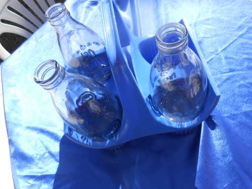 Three glass milk bottle in their plastic carrier.