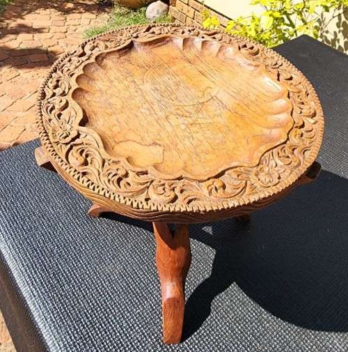 ORIENTAL TEAK COFFEE TABLE  CIRCULAR TOP WITH CARVED FLORAL BORDER AND FOLDING TRIPOD FEET