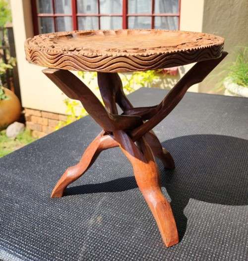 ORIENTAL TEAK COFFEE TABLE  CIRCULAR TOP WITH CARVED FLORAL BORDER AND FOLDING TRIPOD FEET