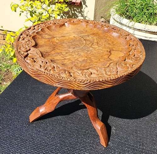 ORIENTAL TEAK COFFEE TABLE  CIRCULAR TOP WITH CARVED FLORAL BORDER AND FOLDING TRIPOD FEET