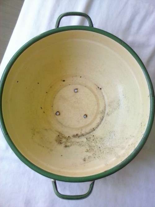 Enamel dish that was used as a flower pot. It has three holes in the bottom.