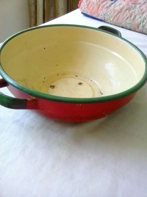 Enamel dish that was used as a flower pot. It has three holes in the bottom.