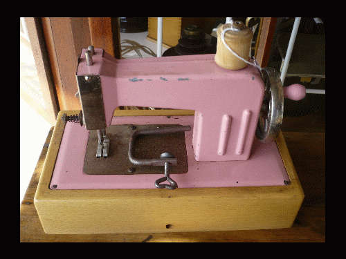 UNMARKED PINK  DOLLS SEWING MACHINE IN WOODEN FRAME