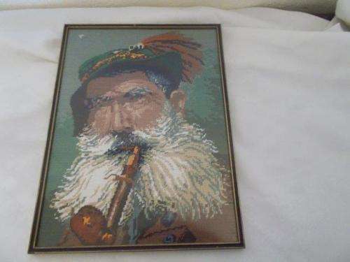 Small framed tapestry of a man smoking a pipe behind glass