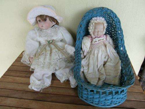 TWO NICE PROCELAIN DOLLS ONE IN A BASKET CRIB