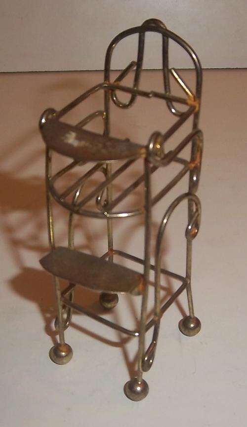 A MINIATURE METAL BABY FEEDING CHAIR FOR A DOLL HOUSE