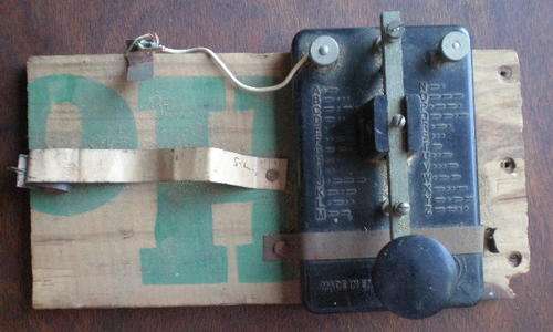 A PIECE OF SIGNAL EQUIPMENT FROM WW2-A MORSE KEY MADE IN ENGLAND  MOUNTED ON A PIECE OF WOOD