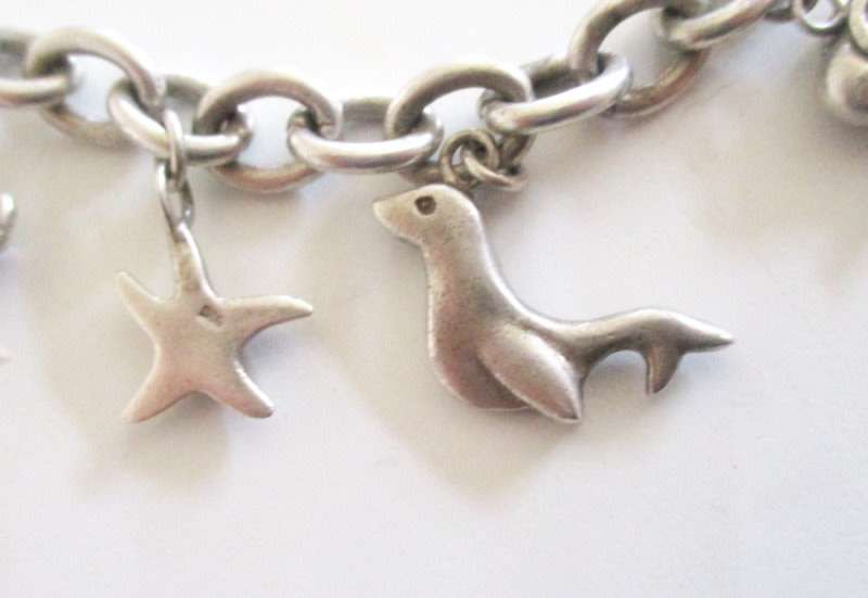 A HEAVY SOLID SILVER CHARM BRACELET WITH LARGE AND MEDIUM SIZE CHARMS--62,5 Gram