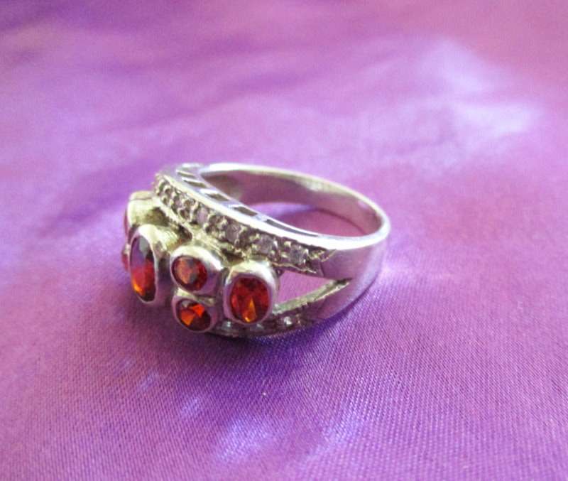 A SOLID SILVER RING WITH RED STONES
