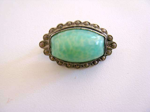 A SMALL VINTAGE BROOCH WITH A GREEN STONE.