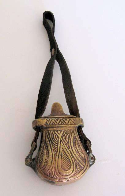 A BRASS POUCH WITH A LEATHER STRAP.