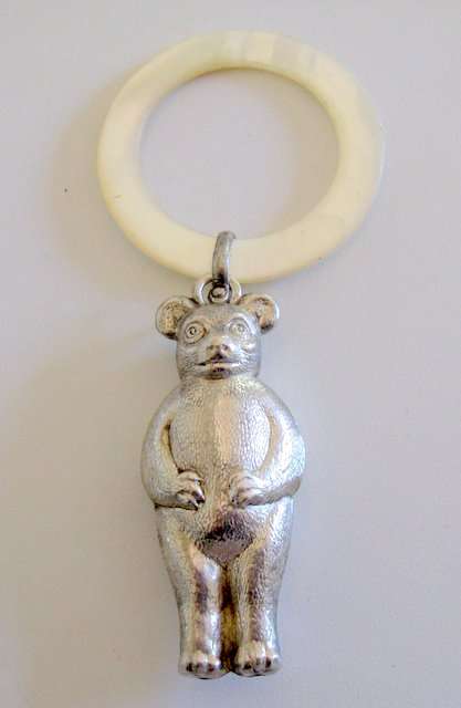 A HALLMARKED SILVER  TEDDY BEAR BABY RATTLE  WITH A MOTHER OF PEARL TEETHING RING.
