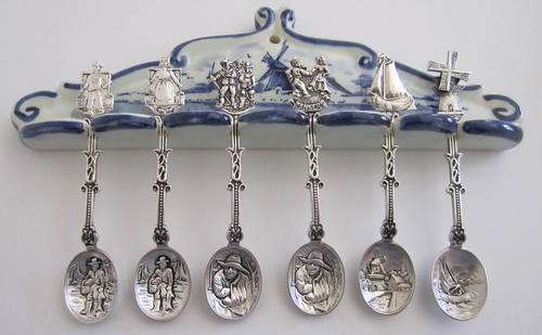 A LOVELY SET OF DUTCH EMBOSSED SPOONS ON A CERAMIC DUTCH STAND