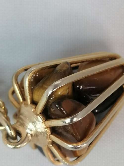 AN UNUSUAL CAGED TIGERS EYE PENDANT ON A GOLD TONE CHAIN