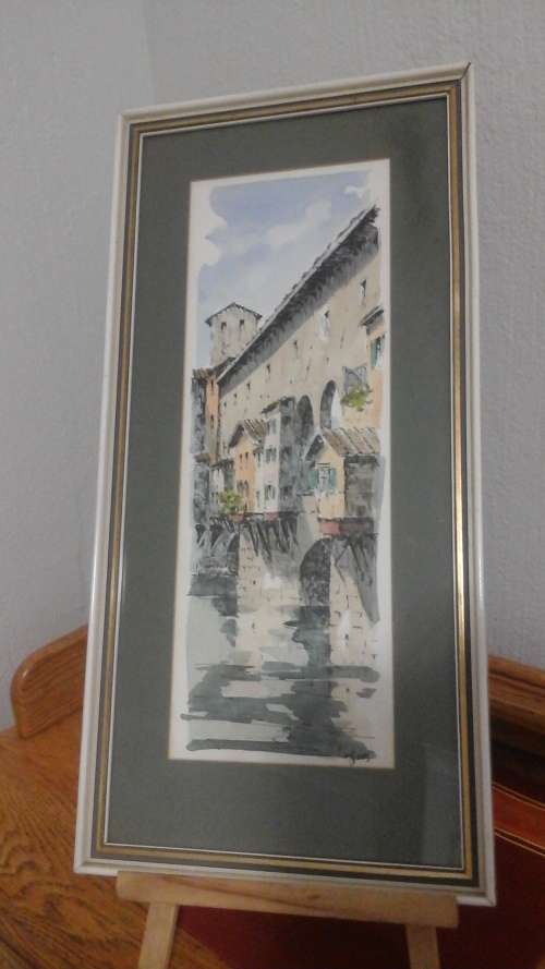 A MAJESTIC SIGNED PRINT OF BUILDINGS IN A WHITE SHABBY SHICK FRAME WIT HA GREEN AND GOLD BORDER.