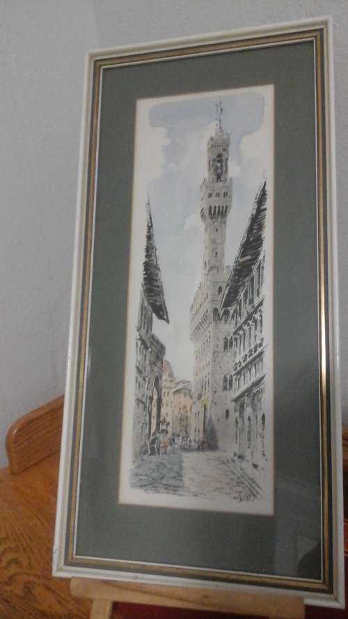 A MAJESTIC SIGNED PRINT OF BUILDINGS IN A WHITE SHABBY SHICK FRAME WITH A GREEN AND GOLD BORDER.