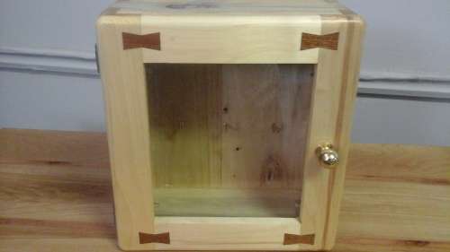 AN UNUSUAL KEY BOX. TAKES SIX KEYS. HAS A GLASS DOOR WITH A BRASS KNOB EVEN HAS DECORATIVE BOWS