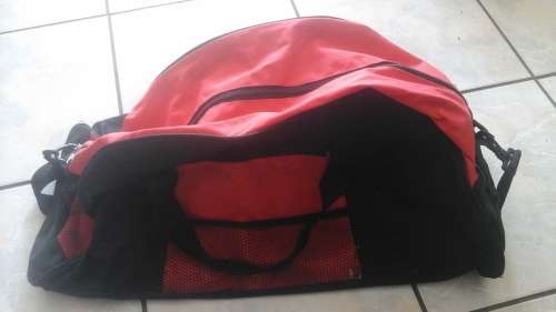 A HANDY RED LIGHTWEIGHT TRAVEL BAG. HAS HANDLES AND A STRAP