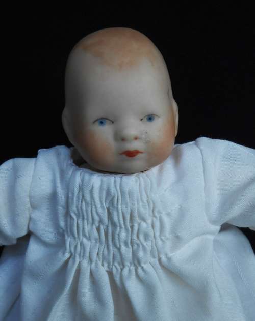 Collectable small porcelain baby doll in nightdress