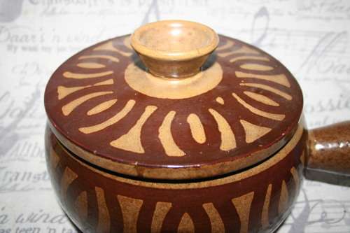 A Large vintage pottery bowl with a lid an explosion of color on both sides and a wonderful handle.