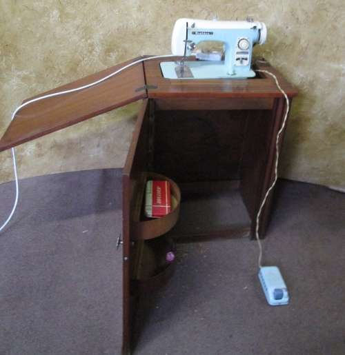 A VINTAGE BROTHER SEWING MACHINE IN A CUPBOARD IN WORKING CONDITION