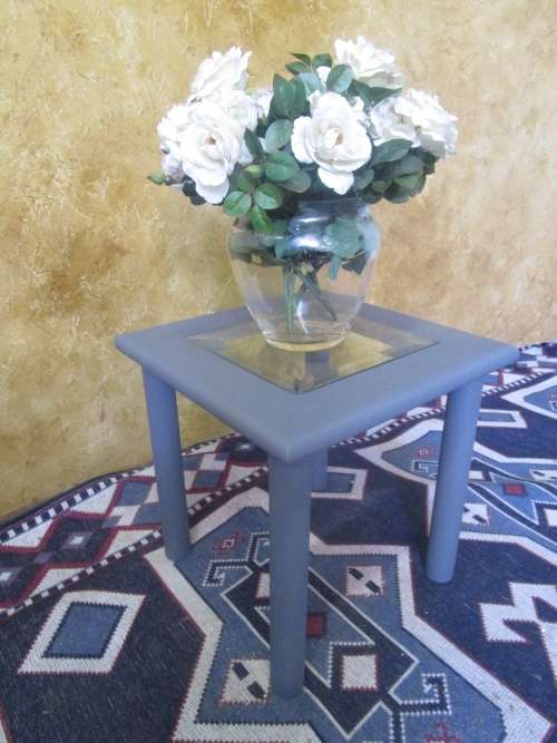 A stunning square chalk painted side table with a glass top