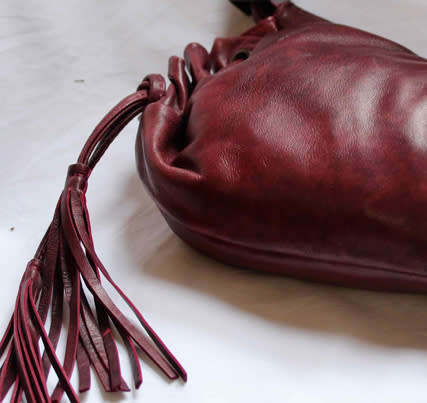 GENUINE JENNIFER LOPEZ (JLO) BURGUNDY ORIGINAL LEATHER 'HOBO' HANDBAG WITH TASSEL DETAILS.