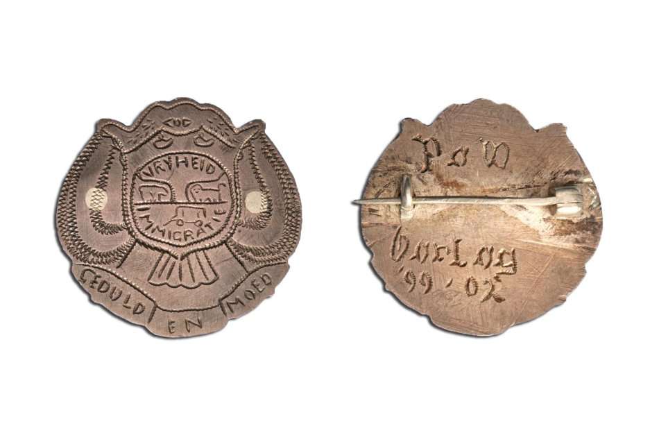 An engraved P.O.W. badge with Vryheid coat of arms and 1899-1902 GEDULD EN MOED with pin