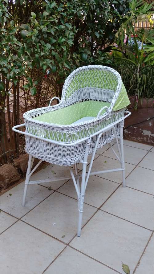 Lovely white cane bassinet on a stand.