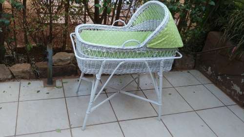 Lovely white cane bassinet on a stand.